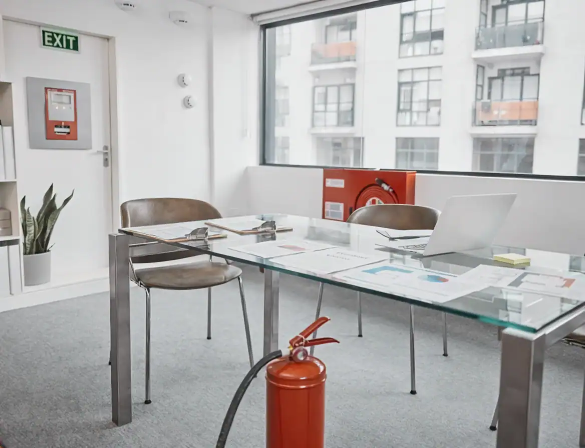 Salle de réunion avec table, chaises, et extincteur rouge.